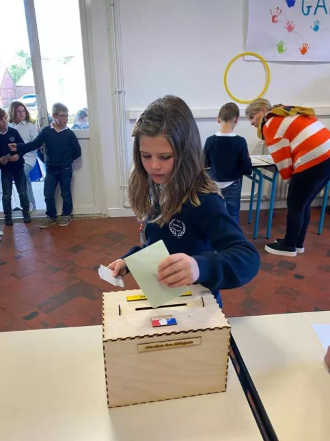 Élève qui place son vote dans l'urne